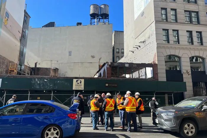 Workers stand outside the building after a wall collapsed on Tuesday.